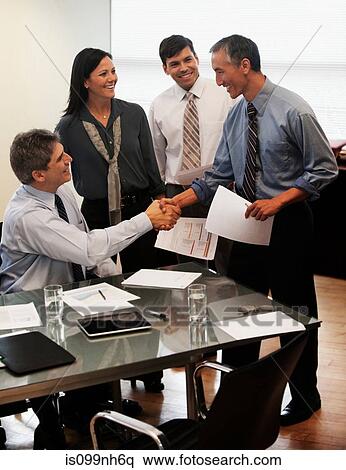 Businessman shaking hands in office with colleagues View Large Photo Image Stock Photography - Businessman shaking hands in office with colleagues. Fotosearch