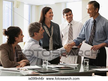 Businessman shaking hands in office with colleagues View Large Photo Image Stock Photography - Businessman shaking hands in office with colleagues. Fotosearch
