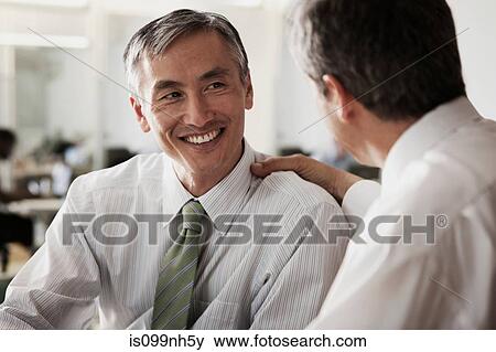 Stock Photo - Businessman touching colleagues shoulder in office. Fotosearch