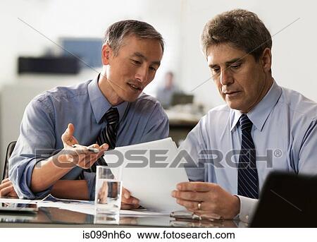 Businessmen discussing report in office View Large Photo Image Picture - Businessmen discussing report in office. Fotosearch
