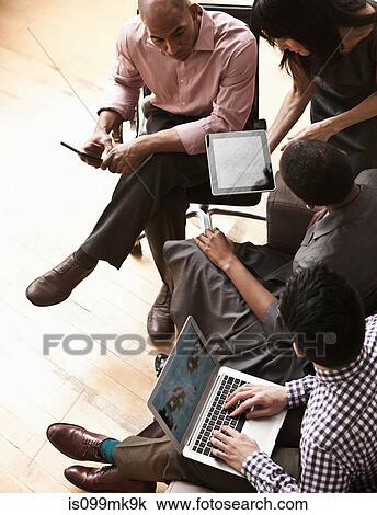 Stock Image - Businesspeople using digital tablet and laptop, high angle. Fotosearch