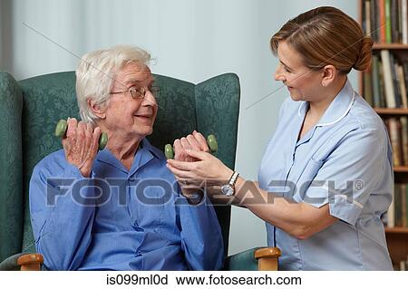 Stock Image - Carer assisting senior man with hand weights. Fotosearch