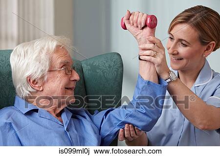 Stock Image - Carer assisting senior man with hand weights. Fotosearch