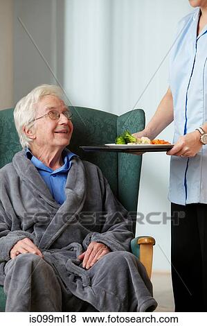 Stock Photo - Carer bringing meal to senior man. Fotosearch