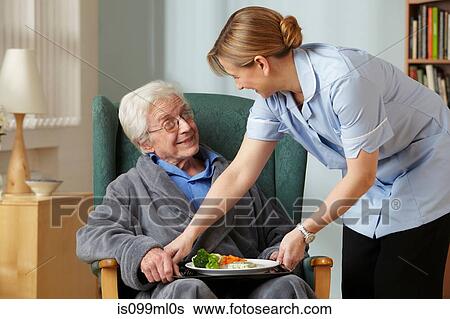 Stock Photograph - Carer bringing meal to senior man. Fotosearch