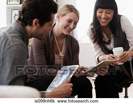 Stock Image - Colleagues using digital tablets in meeting. Fotosearch