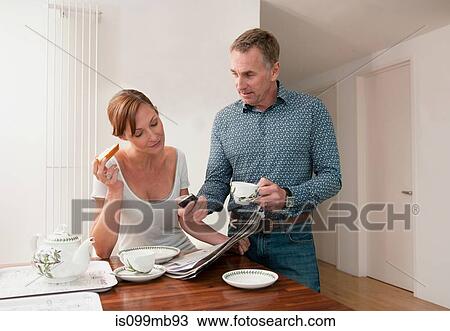 Stock Image - Couple at table with cups of tea. Fotosearch