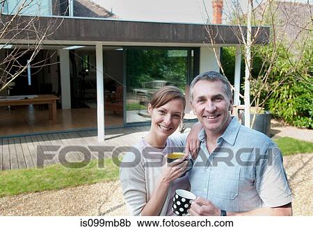 Stock Image - Couple holding mugs, portrait. Fotosearch