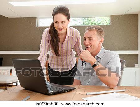 Couple using laptop in home office View Large Photo Image Stock Image - Couple using laptop in home office. Fotosearch