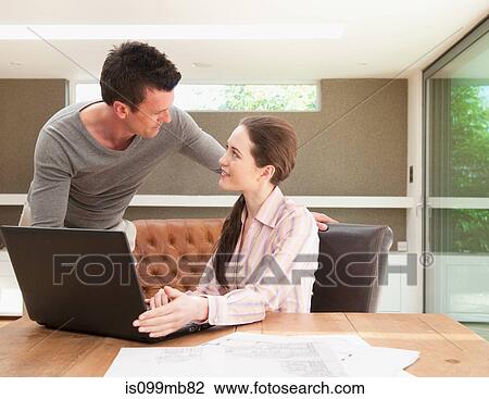 Couple using laptop in home office View Large Photo Image Stock Image - Couple using laptop in home office. Fotosearch