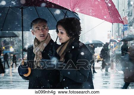 Couple walking through snow in city View Large Photo Image Stock Image - Couple walking through snow in city. Fotosearch