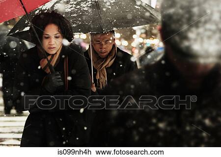 Couple walking through snow in city View Large Photo Image Stock Image - Couple walking through snow in city. Fotosearch