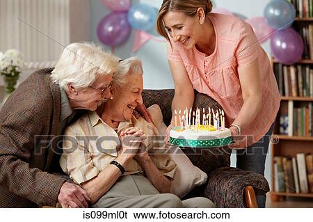 Stock Photograph - Daughter giving birthday cake to senior mother. Fotosearch
