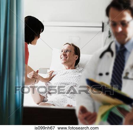Doctor and nurse checking on patient in hospital bed View Large Photo Image Stock Photo - Doctor and nurse checking on patient in hospital bed. Fotosearch
