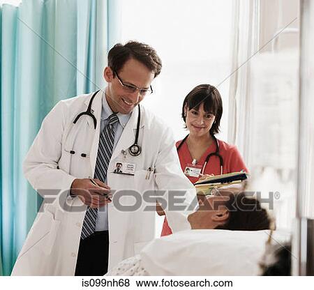 Doctor and nurse checking on patient in hospital bed View Large Photo Image Stock Photo - Doctor and nurse checking on patient in hospital bed. Fotosearch
