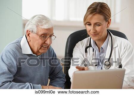 Doctor and senior man looking at laptop View Large Photo Image Stock Image - Doctor and senior man looking at laptop. Fotosearch
