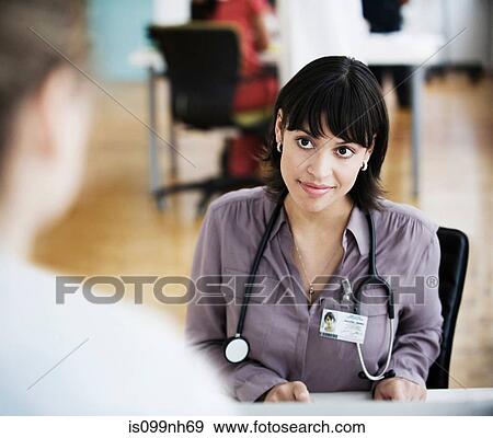 Doctor sitting at desk View Large Photo Image Stock Photo - Doctor sitting at desk. Fotosearch