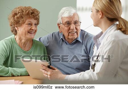 Doctor using digital tablet with senior couple View Large Photo Image Stock Photo - Doctor using digital tablet with senior couple. Fotosearch