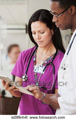Stock Image - Doctors and nurse in discussion over patients records in hospital. Fotosearch