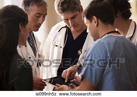 Stock Photo - Doctors discussing patients charts on digital tablet in hospital. Fotosearch