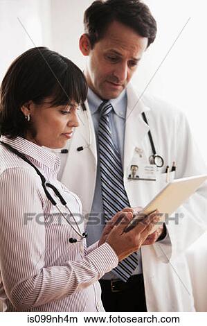 Doctors in discussion over patients records in hospital View Large Photo Image Picture - Doctors in discussion over patients records in hospital. Fotosearch