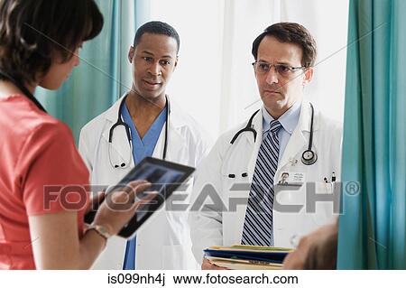 Stock Image - Doctors in discussion with nurse in hospital. Fotosearch