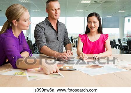 Fashion designers at desk looking at imagery View Large Photo Image Stock Image - Fashion designers at desk looking at imagery. Fotosearch