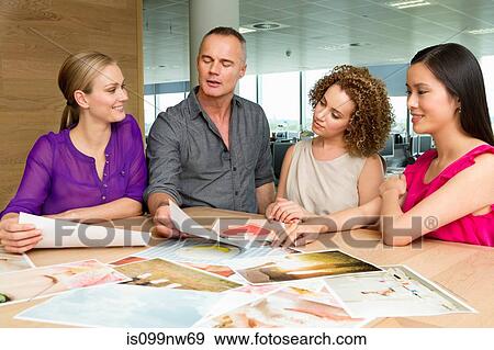 Fashion designers at desk looking at imagery View Large Photo Image Stock Photo - Fashion designers at desk looking at imagery. Fotosearch