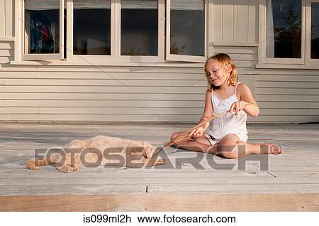Stock Image - Girl and pet cat playing with stick. Fotosearch