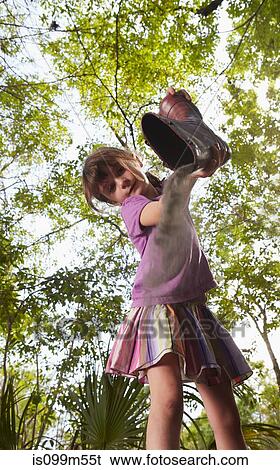 Stock Photograph - Girl emptying dust from wellington boot. Fotosearch
