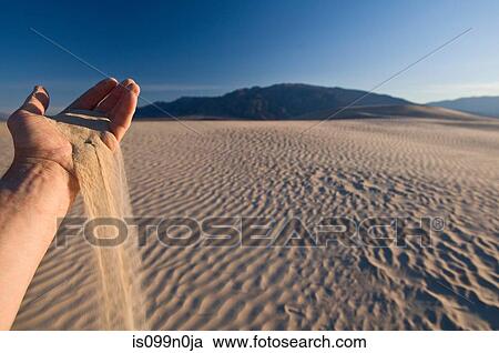 Stock Image - Hand holding sand in Death Valley National Park, California, USA. Fotosearch