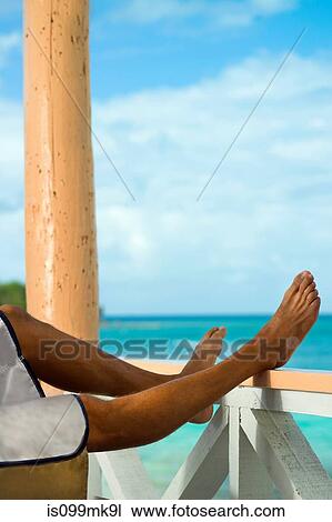 Man on vacation with legs resting on veranda rail View Large Photo Image Stock Image - Man on vacation with legs resting on veranda rail. Fotosearch