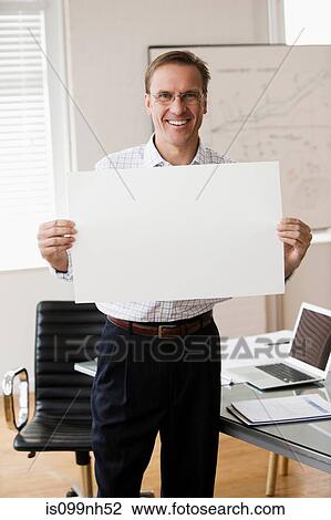Mature businessman holding blank page in office View Large Photo Image Stock Image - Mature businessman holding blank page in office. Fotosearch
