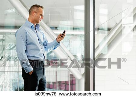 Mature businessman in office using cellphone View Large Photo Image Stock Photo - Mature businessman in office using cellphone. Fotosearch