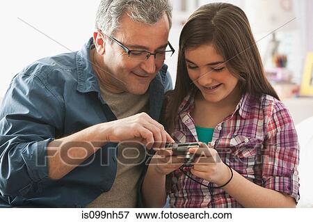 Mature man looking at digital camera with daughter View Large Photo Image Stock Photo - Mature man looking at digital camera with daughter. Fotosearch