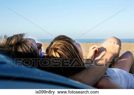 Mid adult couple relaxing on car on beach View Large Photo Image Stock Photo - Mid adult couple relaxing on car on beach. Fotosearch