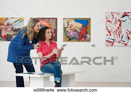 Mid adult woman advising art student drawing in sketch pad in art gallery View Large Photo Image Stock Image - Mid adult woman advising art student drawing in sketch pad in art gallery. Fotosearch