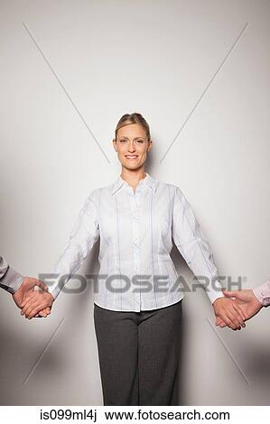 Stock Image - Mid adult woman holding hands with two men, portrait. Fotosearch