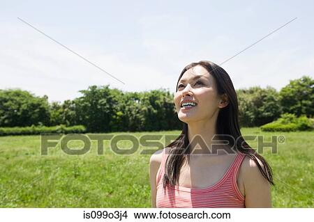 Picture - Mid-adult woman in a field, looking up. Fotosearch