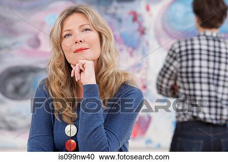 Mid adult woman sitting in front of oil painting in gallery View Large Photo Image Stock Image - Mid adult woman sitting in front of oil painting in gallery. Fotosearch