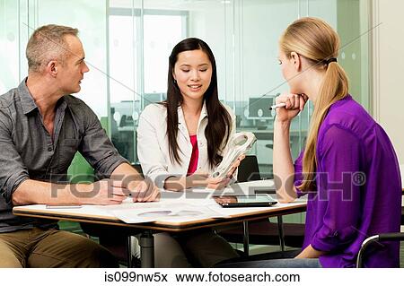Stock Photo - Office colleagues discussing new technologies on desk. Fotosearch