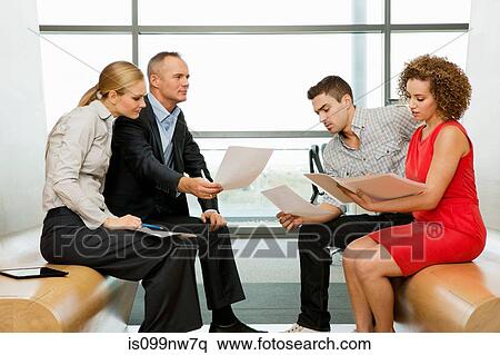 Stock Photography - Office colleagues reading documents in office. Fotosearch