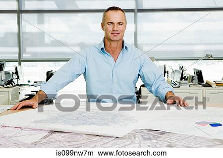 Portrait of an architect working on blueprints in office View Large Photo Image Picture - Portrait of an architect working on blueprints in office. Fotosearch