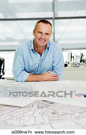 Portrait of an architect working on blueprints in office View Large Photo Image Picture - Portrait of an architect working on blueprints in office. Fotosearch