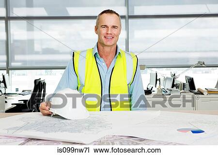 Portrait of an engineer at desk of blueprints in office View Large Photo Image Stock Image - Portrait of an engineer at desk of blueprints in office. Fotosearch
