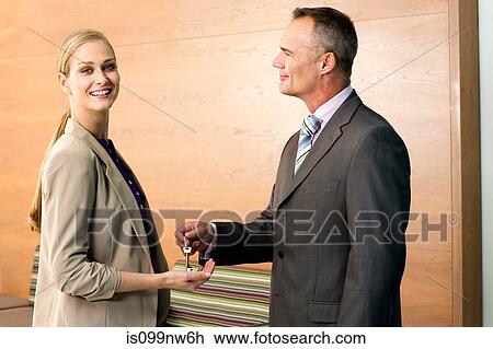 Stock Image - Portrait of estate agent giving keys to customer. Fotosearch
