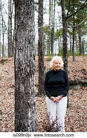 Portrait of senior woman in forest, hands clasped View Large Photo Image Stock Photo - Portrait of senior woman in forest, hands clasped. Fotosearch