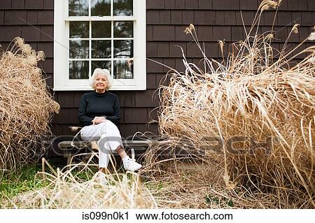 Portrait of senior woman sitting on bench outside house View Large Photo Image Stock Image - Portrait of senior woman sitting on bench outside house. Fotosearch