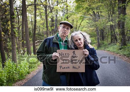 Stock Image - Senior couple holding sign in forest, portrait. Fotosearch