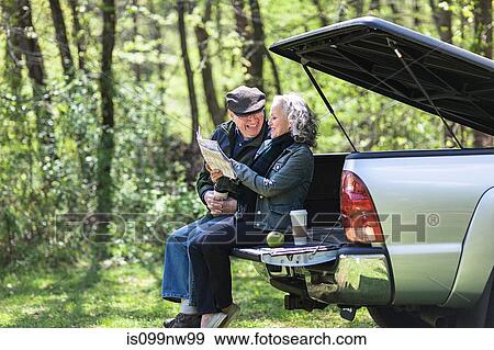 Senior couple reading map while sitting on car trunk in forest View Large Photo Image Stock Photo - Senior couple reading map while sitting on car trunk in forest. Fotosearch